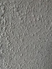 Close-up of a textured painted wall surface, showing rough plaster patterns commonly used in interior and exterior construction finishes.
