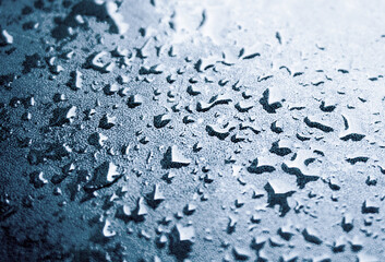 Raindrops clinging to the aluminum handrails. There is colorful bokeh in the background.