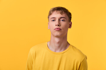 Young man wearing a yellow shirt against a yellow background, studio shot with bright lighting and...