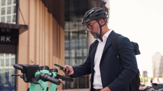 Businessman unlocking electric scooter with smartphone.