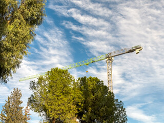 Construction crane arm close-up under bright blue cloudy sky