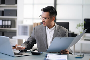 Man calculating finances at home office desk with calculator and papers.
