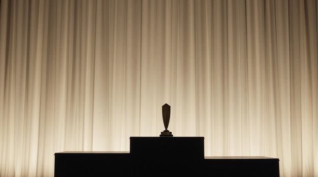 Symbolic trophy on a dark podium against a white curtain backdrop representing abuse and injustice