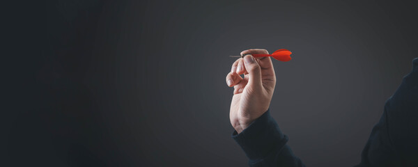 Business action and strategic decision with human hand holding red dart ready to throw, symbolizing...