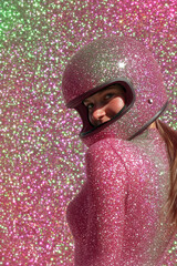 Party background  of a young woman wearing a glittery pink  helmet and outfit against a  pink and green glittery background. Space for text. 