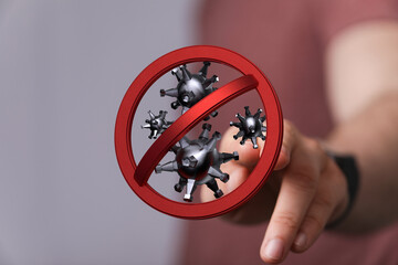 Hand pointing at a red forbidden sign with virus symbols. Concept of fighting against the virus. Prevent the s