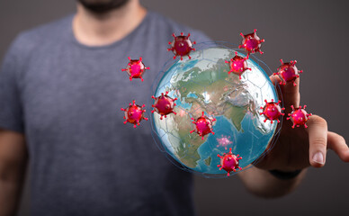 Conceptual image of hand interacting with a globe surrounded by coronavirus particles, representing global spr