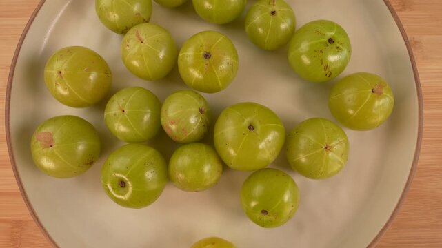 Indian gooseberry fruits on plate rotation top view. Amla. Phyllanthus emblica.