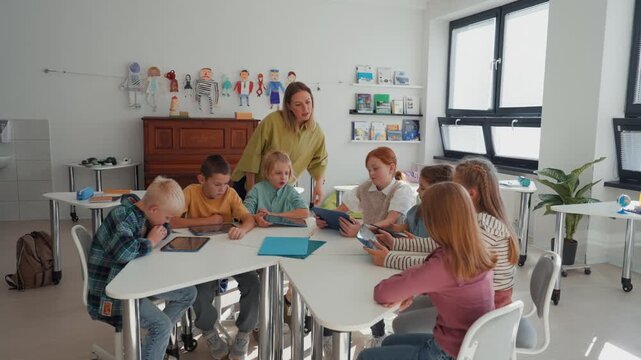 Group of schoolkids using tablets and laptops in class.