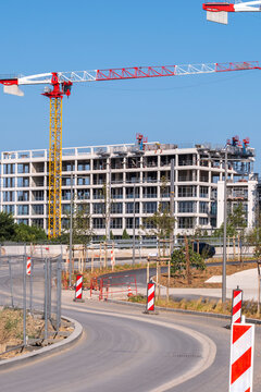 Wide access road beside construction site with tower crane and building development showing architecture urban engineering infrastructure property project
