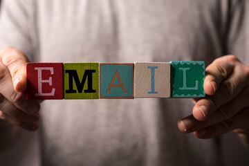 Close-up of a person holding letter blocks spelling the word Email. Concept of communication, message, inbox, an