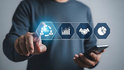 A person interacting with a holographic interface displaying business analytics, teamwork, partnership, and data visualization icons, holding a smartphone.