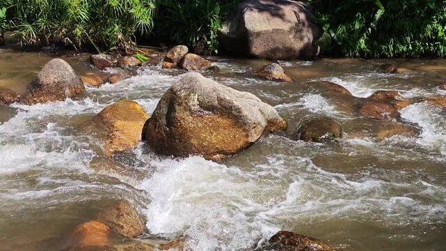 Rapidly flowing mountain river stream water motion over brown stone rock surfaces creating white splash foam peaceful nature forest landscape showing energetic wild beauty outdoors refreshing calm