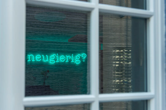 Voyeuristischer Blick durch ein B&uuml;rofenster mit dem Schriftzug Neugier