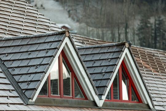 Unique architectural detail of a house roof with triangular windows in the mountains.