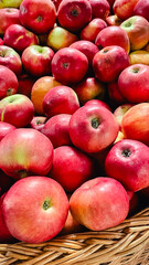 Close-up of fresh ripe red and yellow apples in a wicker basket at a local market or grocery store