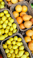 Fresh yellow lemons and orange grapefruits in wicker baskets at a local market or grocery store