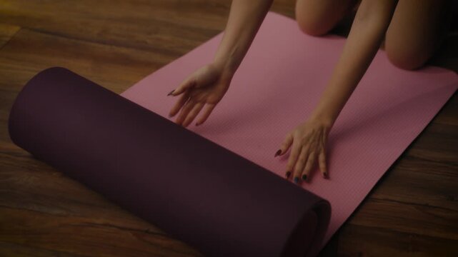 woman practising yoga in a cosy living room setting. She is in a lunging pose on a yoga mat, with a tablet in front of her displaying a workout or meditation session. 