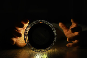 Hands Holding Mesh Sphere in Dramatic Low Light with Artistic Shadows