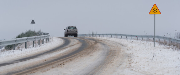 SNOWY WINTER - A snow-covered local road and a sign warns drivers of icy or slippery road conditions ahead