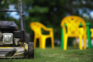 Fototapeta premium Lawn mover on green grass in modern garden. Machine for cutting lawns.