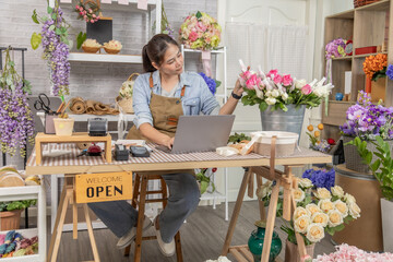 Florist shopkeeper small business owner arranging fresh flowers while checking tablet orders, creative retail startup entrepreneur, customer service focus, modern flower shop lifestyle with technology