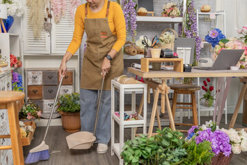 Florist shopkeeper startup small business owner cleaning flower shop alone after workday, responsibility, realistic early stage retail business routine, multitasking daily routine, business challenge