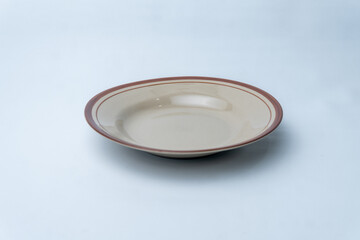 Empty round stoneware plate with a simple vintage brown border. Perfect for rustic food styling, restaurant menus, and traditional dining concepts.
