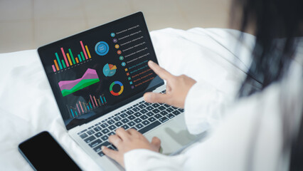 Businesswoman analyzing financial data charts on laptop while working from home