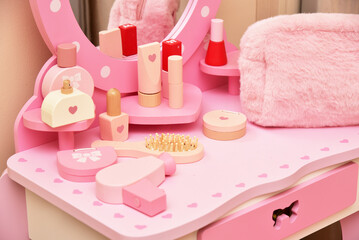 Furniture table with mirror and toy wooden cosmetics in pink colors for a little girl's room