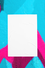 Closeup of colorful messy painted urban wall texture with wrinkled glued poster template. Modern...