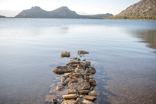 Peaceful Stone Pathway Leading into the Calm Blue Waters of Lake Vouliagmeni in Perachora, Greece