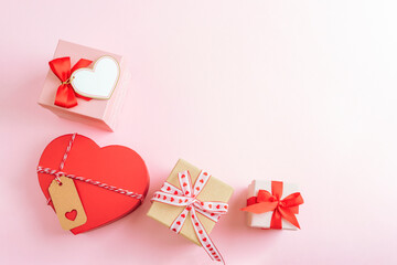 Romantic gift boxes with hearts arranged on soft pink background with copy space. Valentines day concept. Top view, flat lay