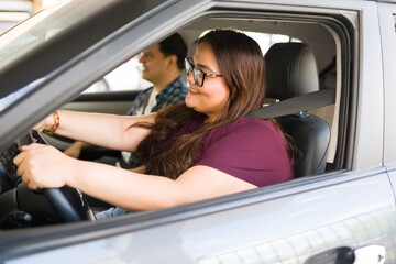 Woman driving with partner in passenger seat, laughing and enjoying a joyful road trip together through city and countryside vistas