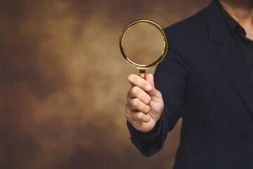 Businessman holding magnifying glass for search concept.