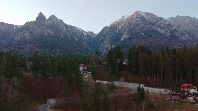 Aerial drone footage of Busteni town with the Caraiman Mountains in the background, filmed in winter daylight. 