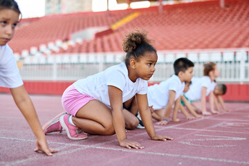 Young children having athletic exercise class running on the track, healthy lifestyle and children sport education concepts, start line preparation for the race