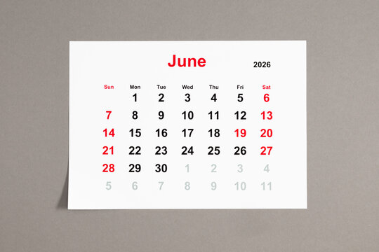 A close-up of a monthly tear-off calendar for June 2026 with weekends highlighted in red. The week starts on Sunday. Calendar sheet on a neutral gray background