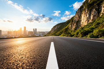 Asphalt Road Leading to Urban City Skyline with Hills