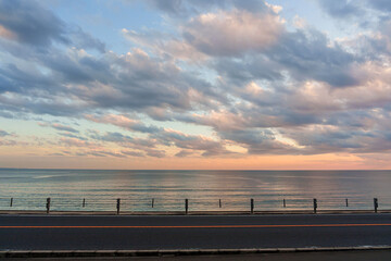 Scenic asphalt coastal road with the sea and colorful evening sky as the backdrop.