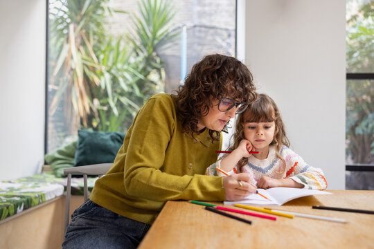 Mom teaching daughter how to write at home