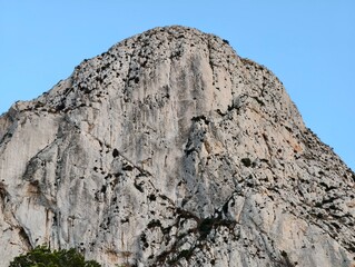mountain face featuring cracks and shadows, rugged rock surface with visible fissures and shadows