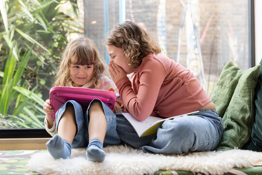 Girls Sharing a Secret While Using a Tablet Together
