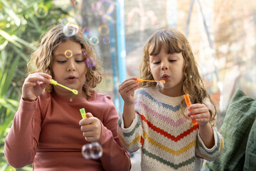 Sisters Blowing Bubbles in a Bright Setting