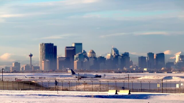 Calgary Skyline View From Snowy Airport Tarmac With Airplane and Rocky Mountains in Alberta, Canada. 