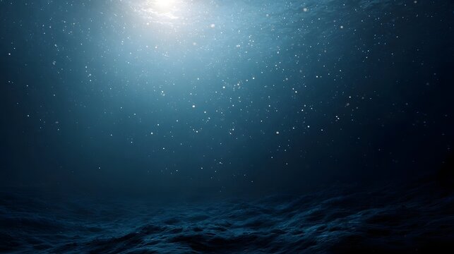 Sunlight beams pierce the deep blue ocean illuminating floating particles above a textured seabed