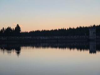 Naklejka premium peaceful industrial reflection, quiet reservoir scene blending engineering with natural beauty