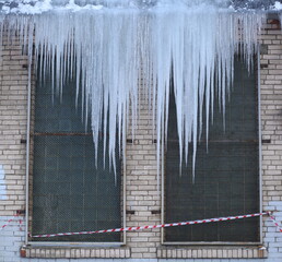 A row of long icicles above the windows in the brick wall