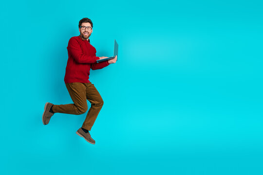 Young man jumps with laptop against blue background showing energy style and casual business mood