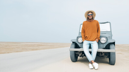 Naklejka premium Man smiling, leaning on vintage off road vehicle, enjoying road trip adventure and travel lifestyle in desert